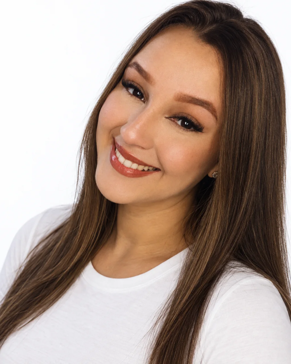 Julia, lash designer da Julia Beauty, sorrindo em retrato sobre fundo claro.